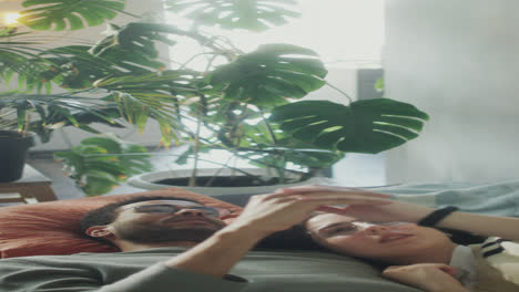 romantic couple lying on sofa and touching hands