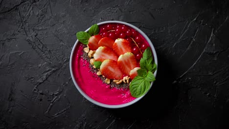 Summer-berry-smoothie-or-yogurt-bowl-with-strawberries--red-currants-and-chia-seeds-on-black