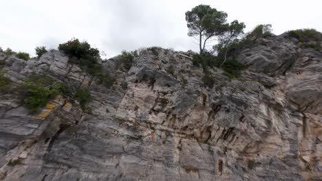 dynamic fpv drone footage flies along rugged limestone cliffs covered in green vegetation, ligurian sea, noli, italy. aerial
