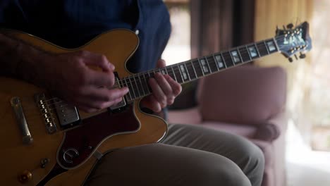 close up view of a man playing an electric guitar in a home studio.