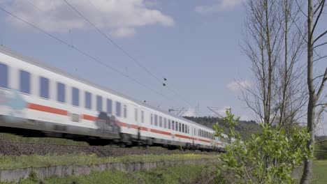 high-speed train rushing through a lush countryside landscape on a sunny day