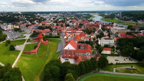 drone shot of the historic old kaunas old town with red brick kaunas castle, churches, town hall in with vytis statue and ukrainian flag in kaunas old town, lithuania on a sunny day, 4k