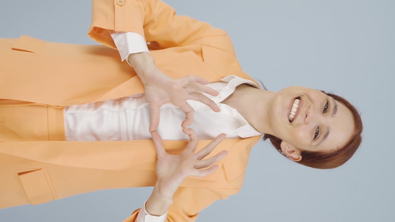 비즈니스 여자가 카메라에 심장을 만드는 수직 비디오.