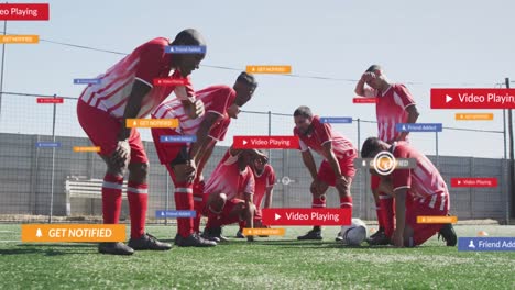 animation of social media icons over tired diverse male soccer players taking break on sports field