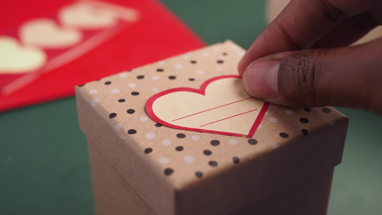 Hand decorating a gift box with a heart-shaped label