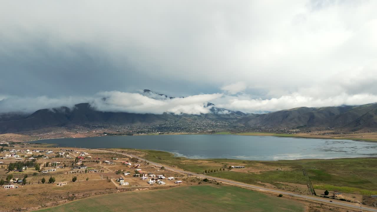 hermosa vista del gran lago y las montañas nubladas en el horizonte, campos verdes y marrones a su alrededor, cámara lenta y copia del espacio