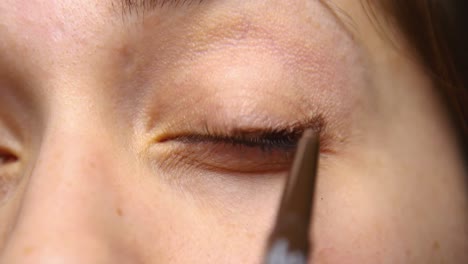 woman applies eyeliner to her upper lid