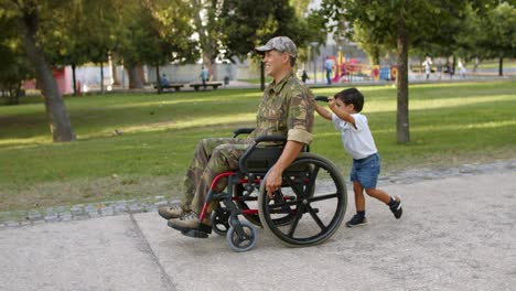 cute boy wheeling with disabled military dad