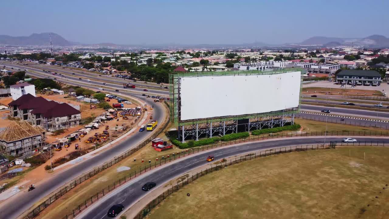 Impresionante vista aérea de coches circulando por una rampa de acceso de una autopista concurrida y pasando una valla publicitaria grande y vacía en Abuya, Nigeria