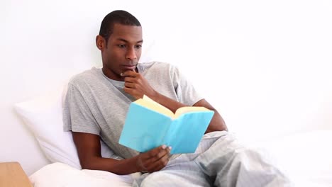 relaxed man lying on bed reading