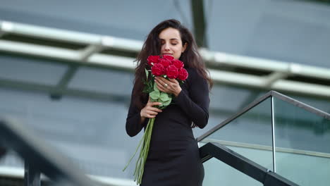 smiling woman smelling red roses outdoors