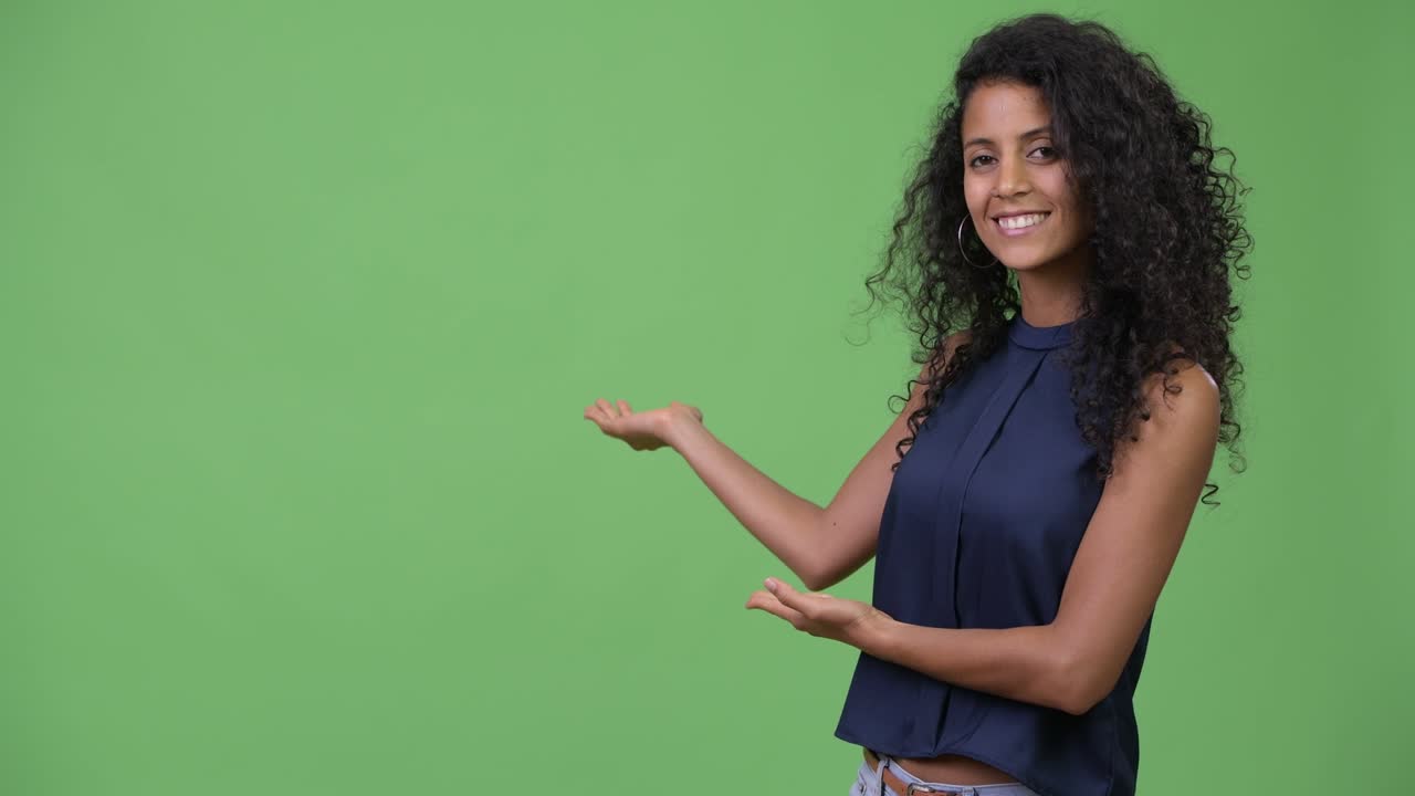 Young beautiful Hispanic businesswoman showing something