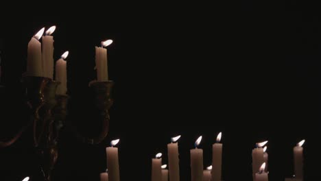 a group of white candles some on a candelabra lit up and running for a while