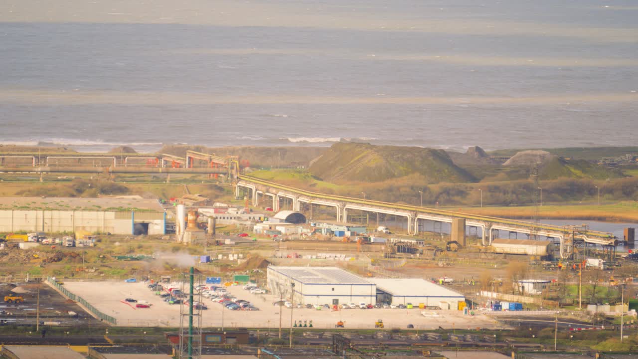Paisagem industrial de siderúrgica: ponte ferroviária que leva ao mar para exportação de aço acabado.