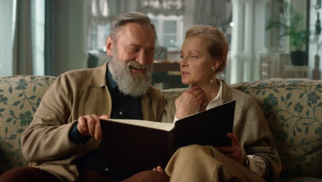 una elegante pareja de mayores mirando el álbum familiar en el interior