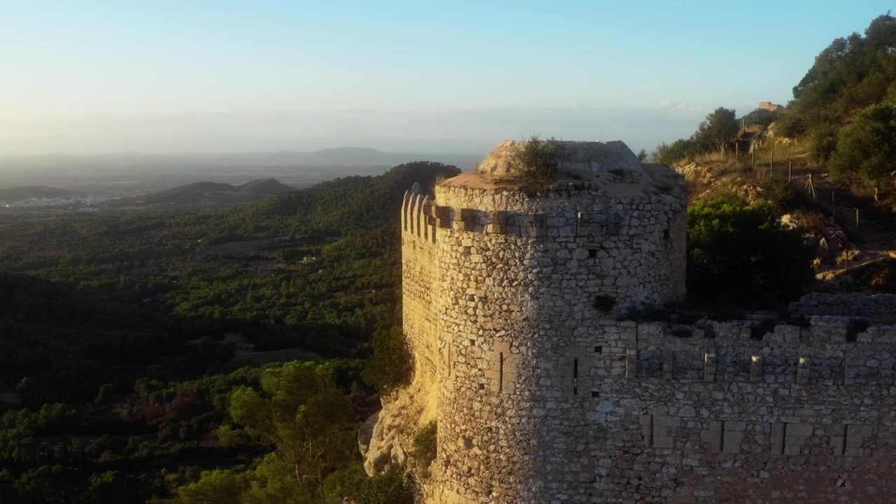 Drone che si alza accanto a una torre di pietra rivelando la valle a Sant Salvador, Maiorca