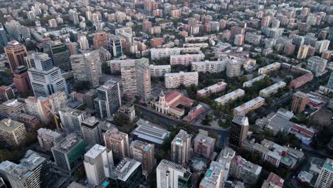 aerial orbit of buildings and divina providencia church in residential neighborhood at golden hour, santiago city, chile