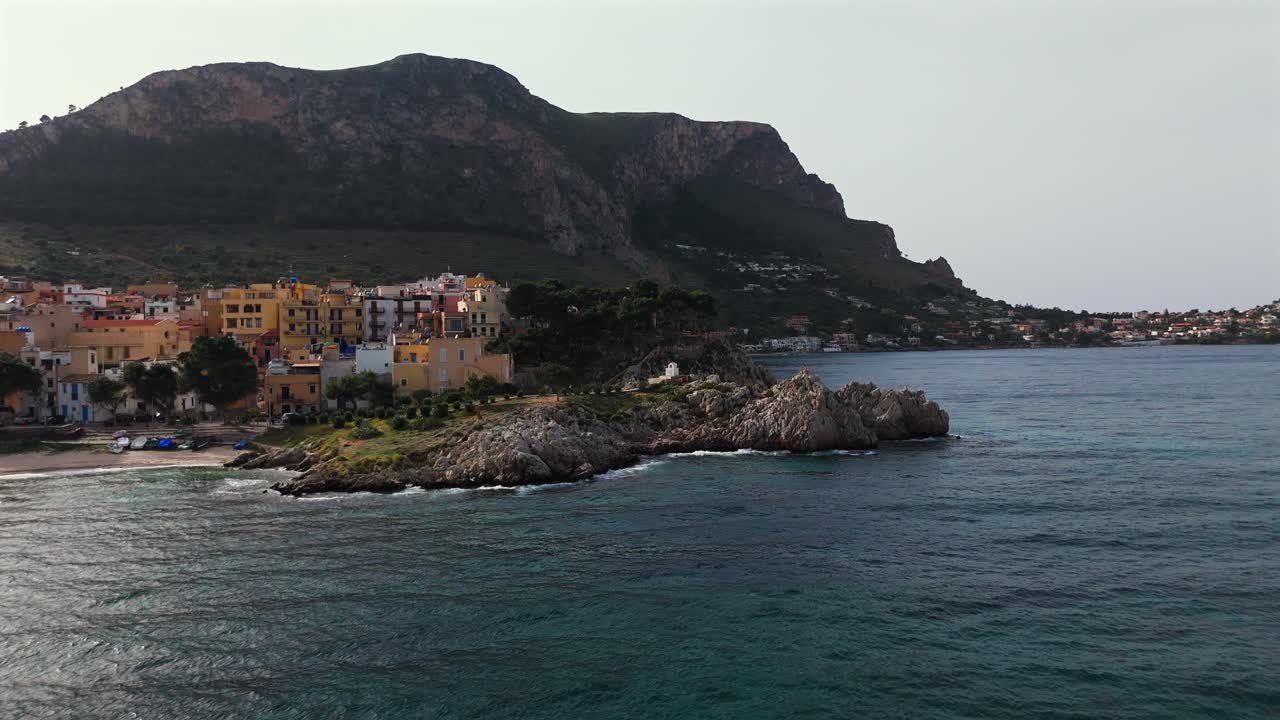 Slow motion 4K drone footage of the coastal town Porticello in Sicily Italy featuring colorful buildings rocky cliffs sea waves and Monte Catalfano with views toward Aspra and Capo Zafferano
