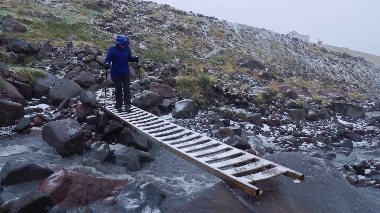 turista caminando a través de la peligrosa escalera a través del río desde el glaciar, cáucaso, georgia