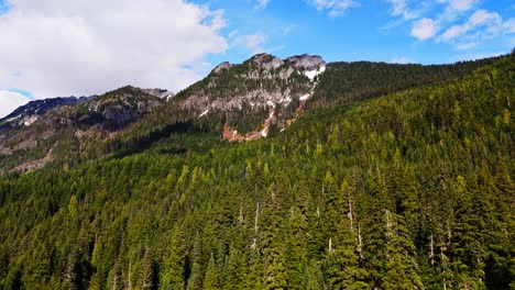 beautiful aerial view flying over evergreen forest towards a mountain at gold creek pond in washington state