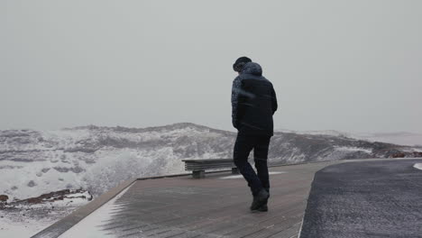 hombre solitario sobre la nieve en el frío paisaje invernal de islandia caminando hasta el mirador del cañón