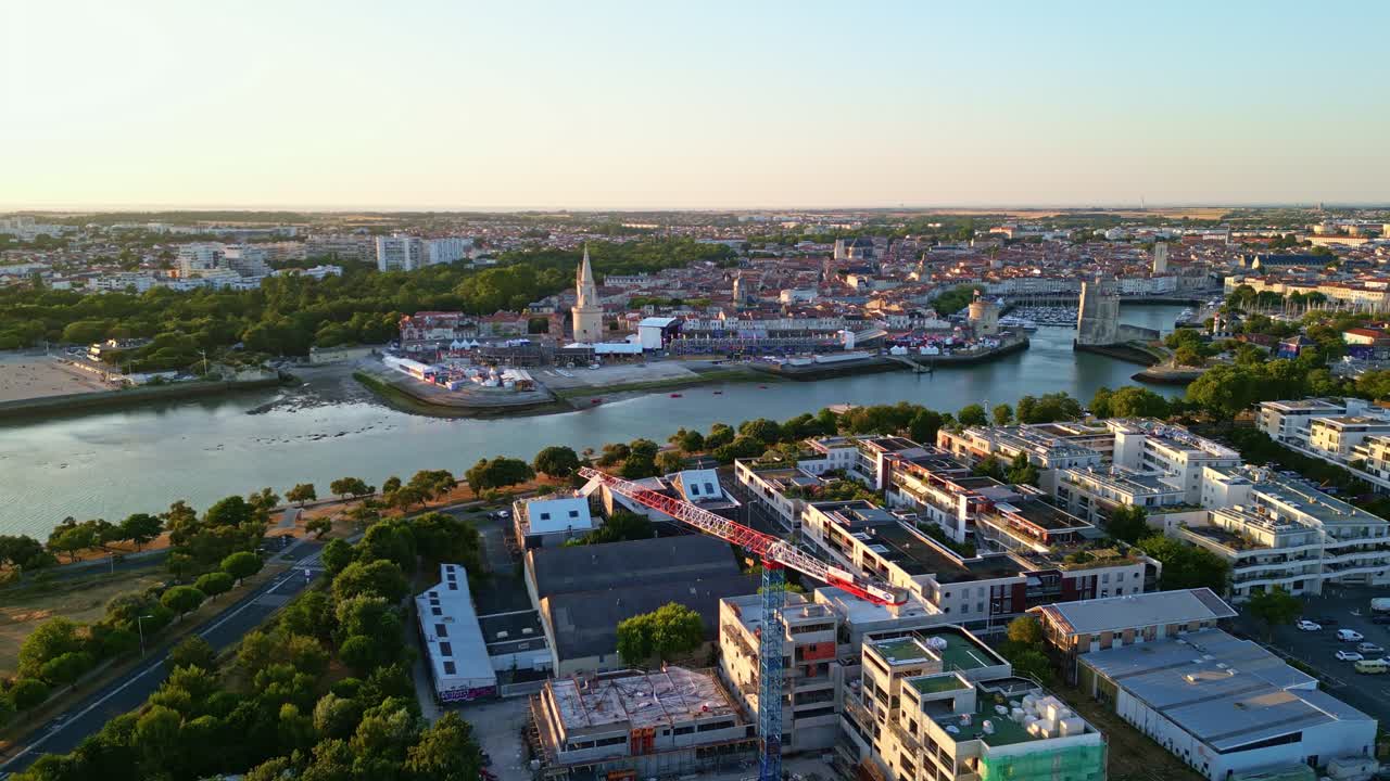 Old Port and cityscape of La Rochelle in background during golden hour, urban development, France. Aerial drone forward