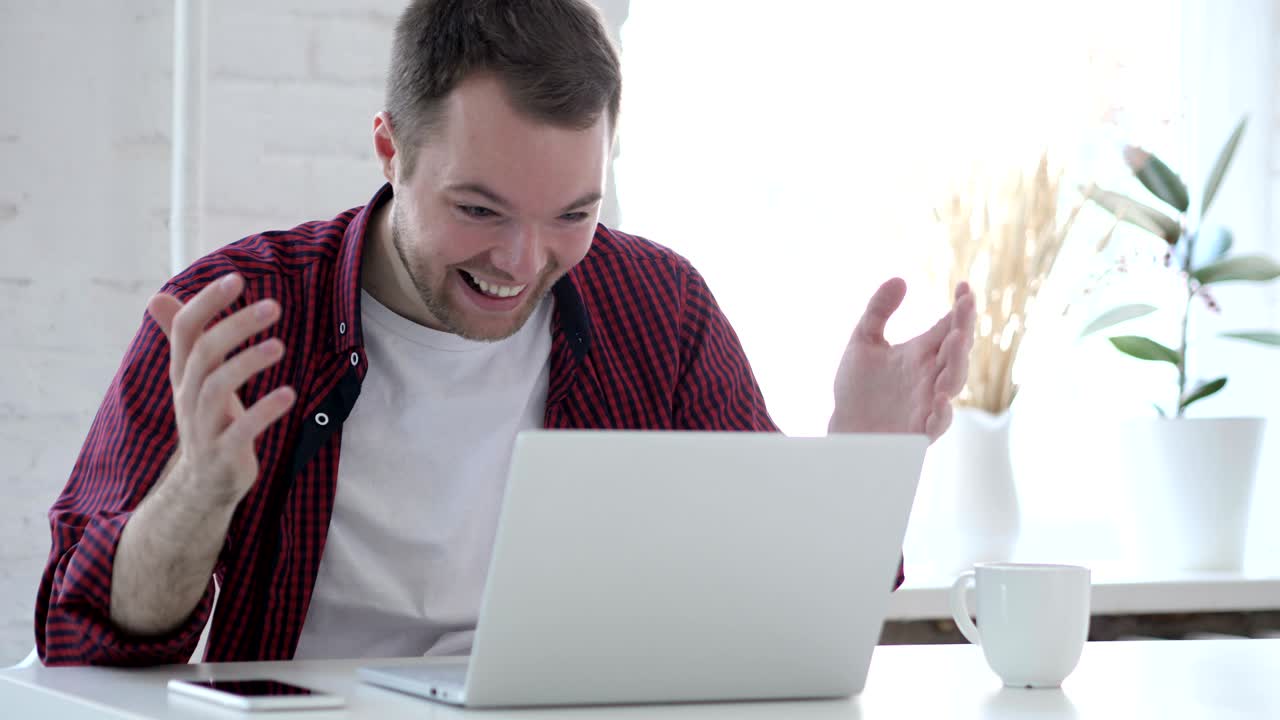 성공을 축하하는 흥분한 젊은이, 노트북에서 일하고