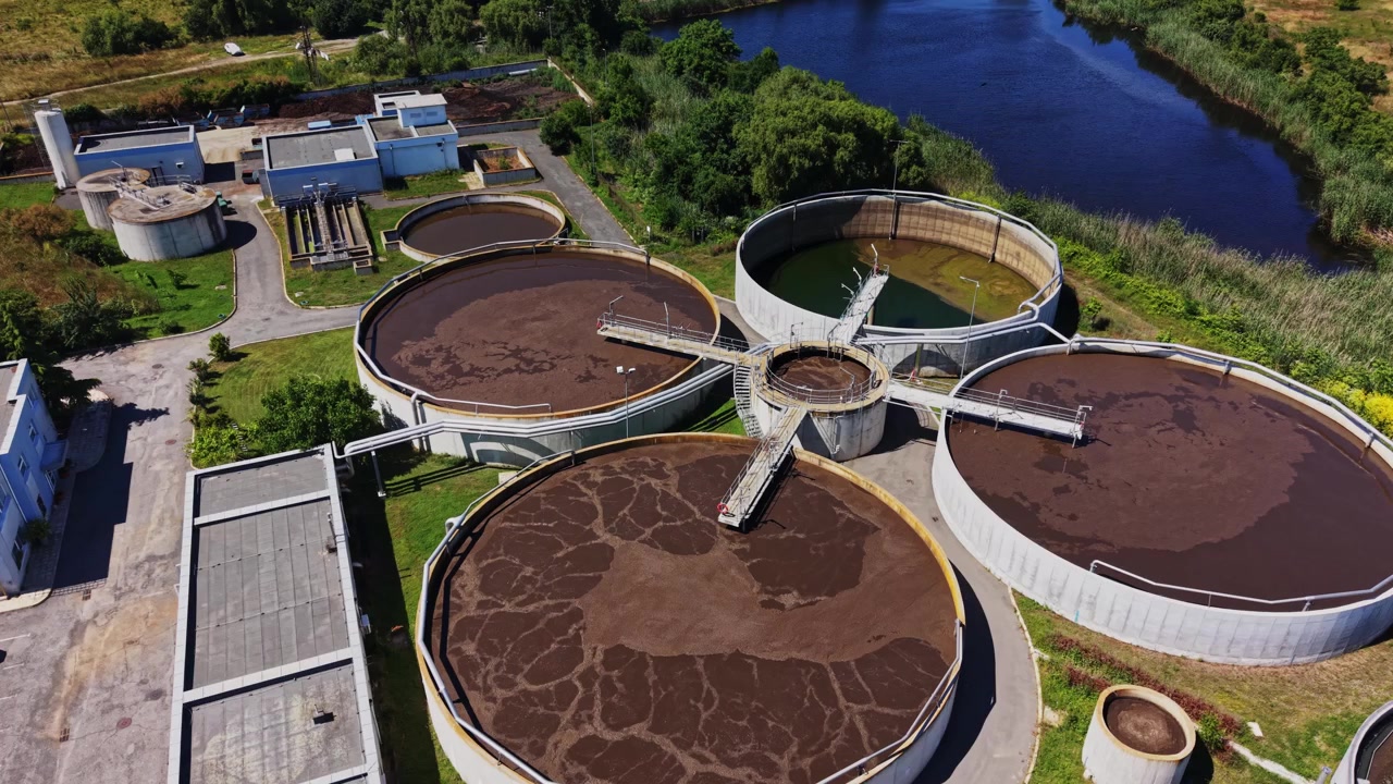 Planta de tratamiento de agua en funcionamiento cerca de un río en un día soleado.