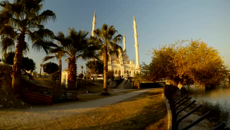 sabanci merkez mosque on the river seyhan with palm trees, summer sunny morning