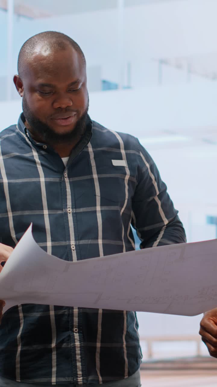 African American Architect Discussing Blueprints in Modern Office