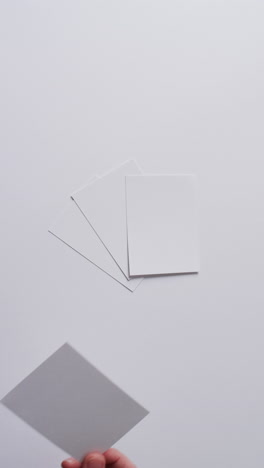vertical video of hand holding piece of paper over pieces of paper with copy space in slow motion