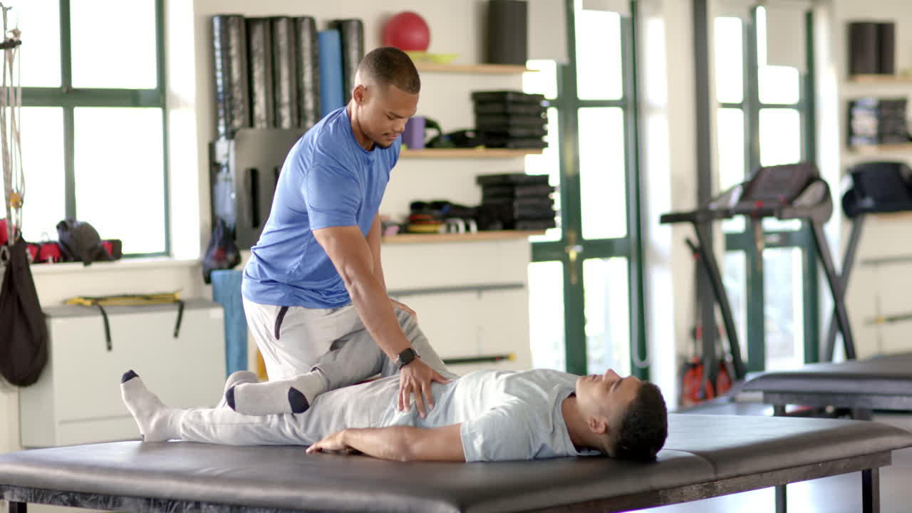 Assisting man with leg exercises, physical therapist in rehabilitation center