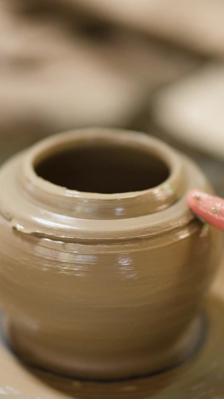 Primo piano delle mani di un vasaio che rifiniscono un manufatto in ceramica su un tornio a Nonthaburi.