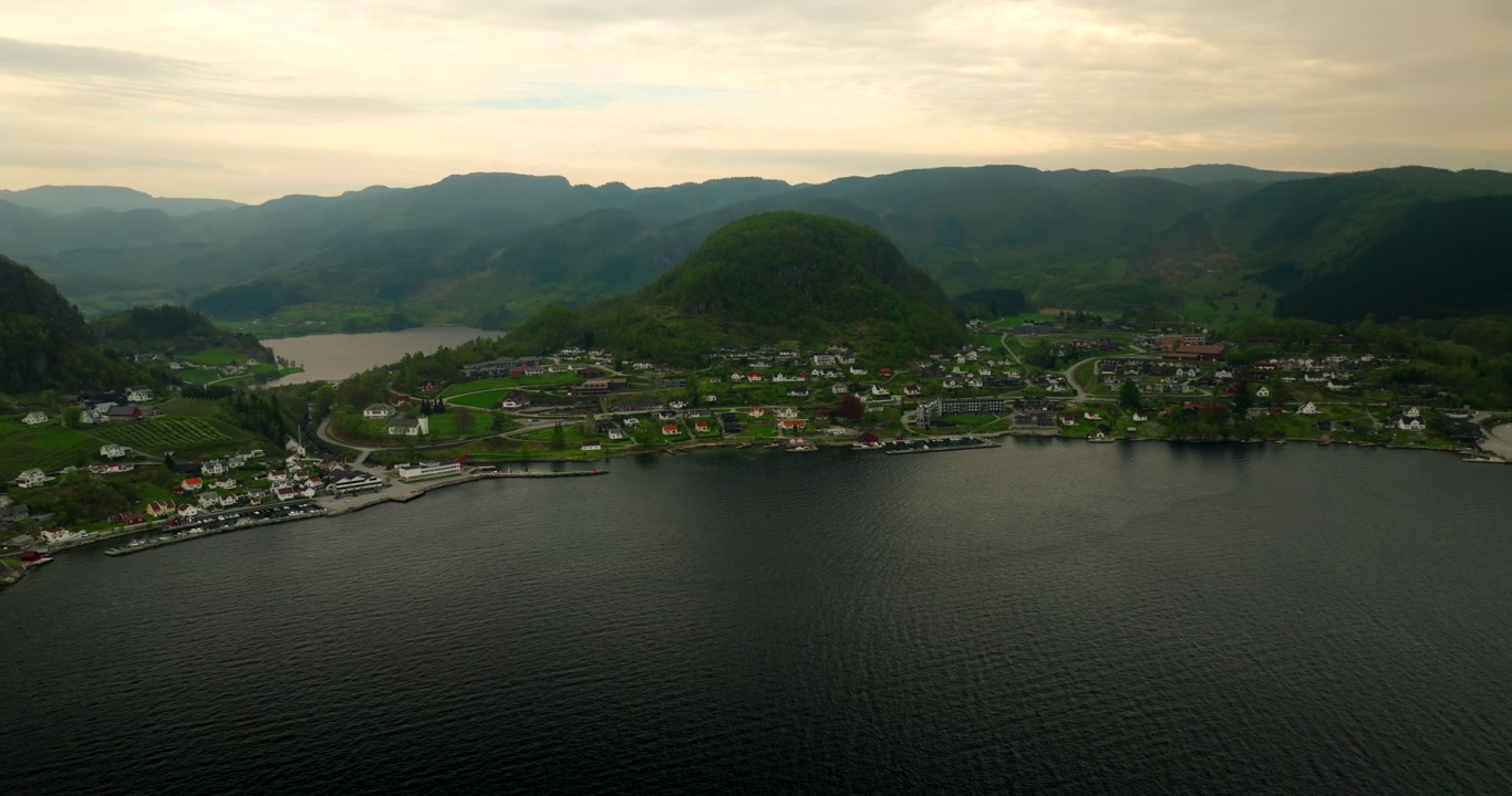 Drone establishing of Hjelmeland town Norway, coastal waterfront buildings and mountains at sunset