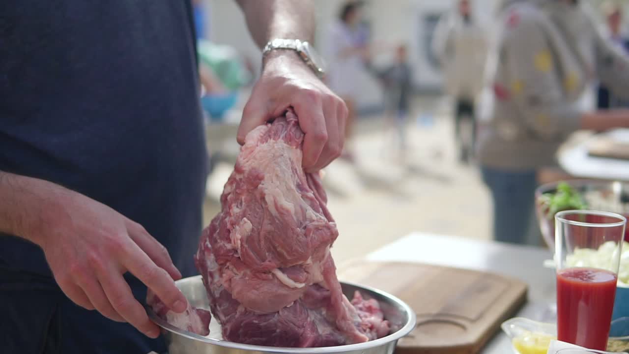 Person's hands preparing a large piece of raw meat for cooking. The wooden surface outside. Barbeque time. shot in 4k
