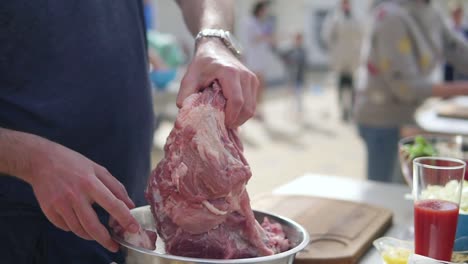 person's hands preparing a large piece of raw meat for cooking. the wooden surface outside. barbeque time. shot in 4k