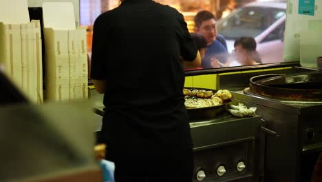 chef prepares buns at a street food stall