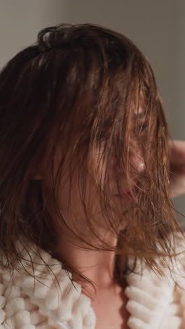 dama posa frente al espejo secando el cabello en la ducha. joven hembra mueve la cabeza con el cabello mojado con emociones positivas en un lugar espacioso movimiento lento