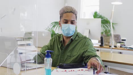 Man-wearing-face-mask-reading-a-document-at-office