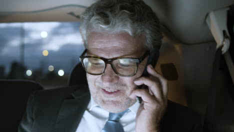 cheerful senior businessman in car talking on phone