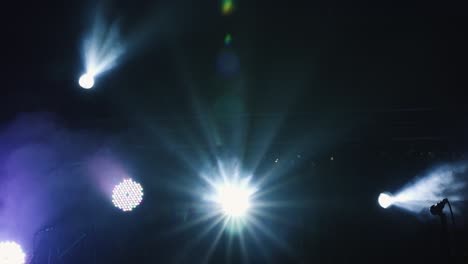 micrófono en el escenario con humo azul y luz detrás de él. plano cercano de ángulo bajo de mano