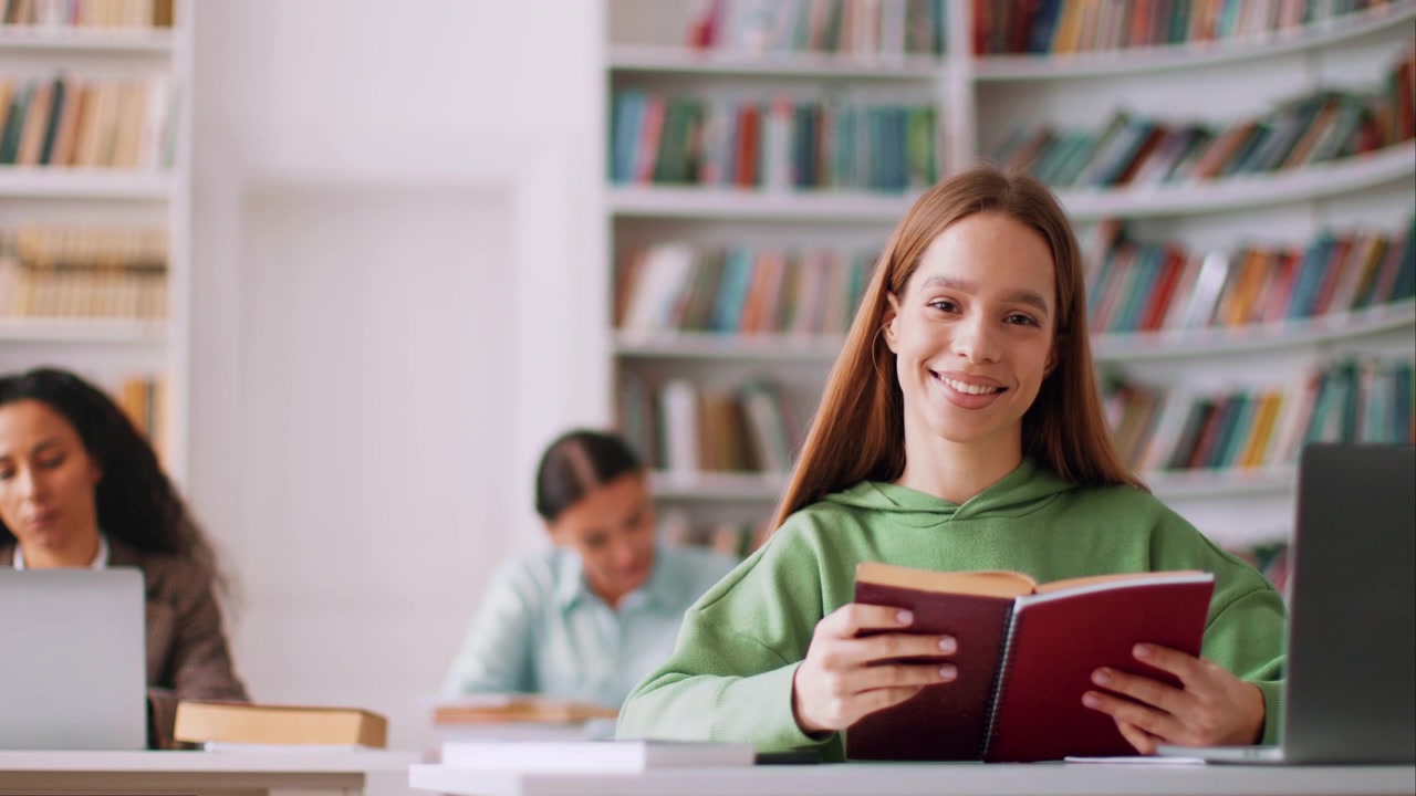 Donna sorridente che legge un libro in biblioteca