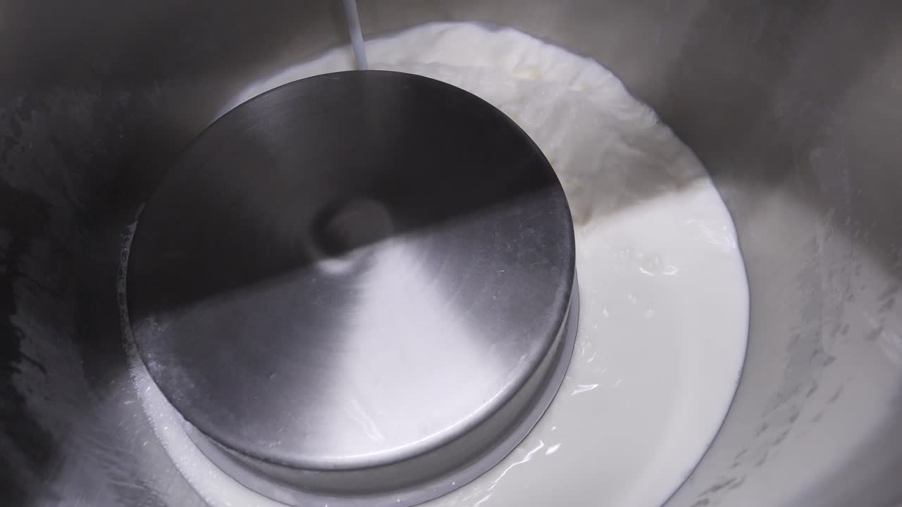 dentro de la tina de acero, llenando el caldero de fábrica con leche para el proceso de pasteurización