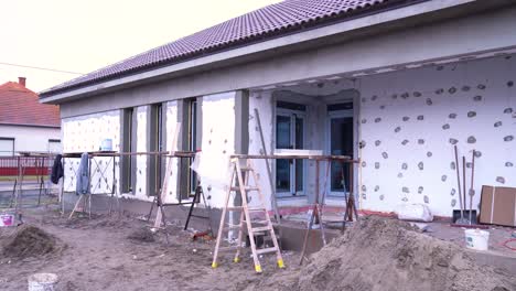 scaffolding and ladders placed along house wall with visible insulation anchors