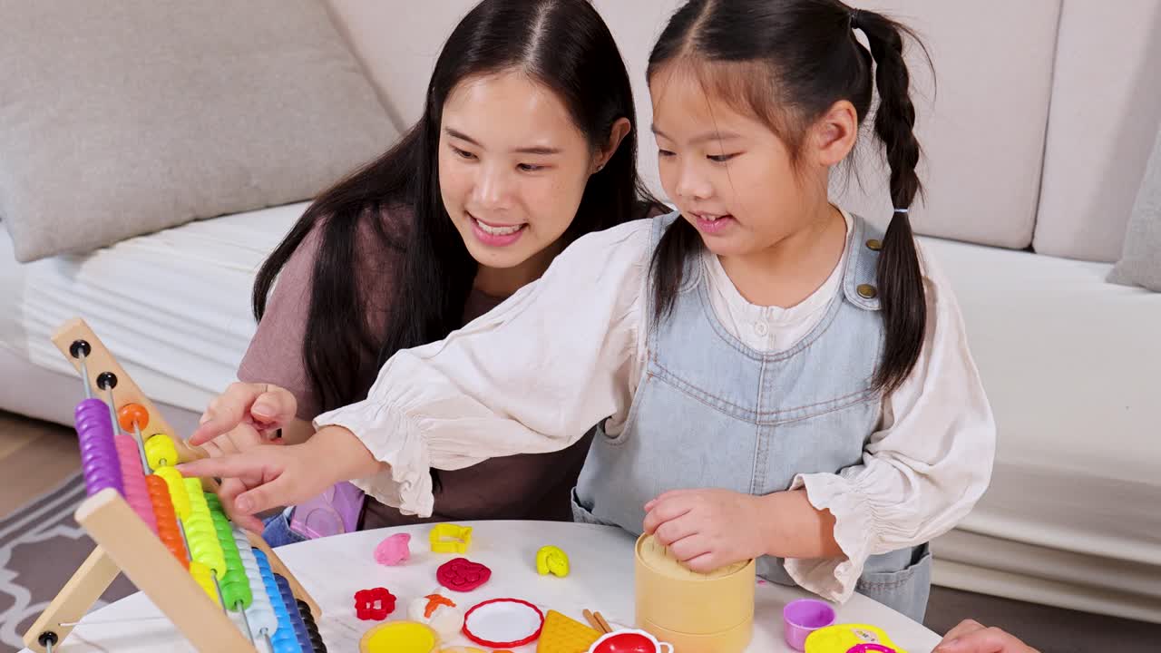 Asian mother and daughter play and learn with colorful abacus in bright, cozy living room
