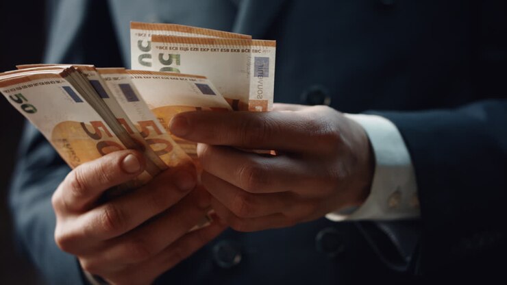 Gros plan sur des mains comptant des coupures de cinquante euros. Un homme calcule des espèces.