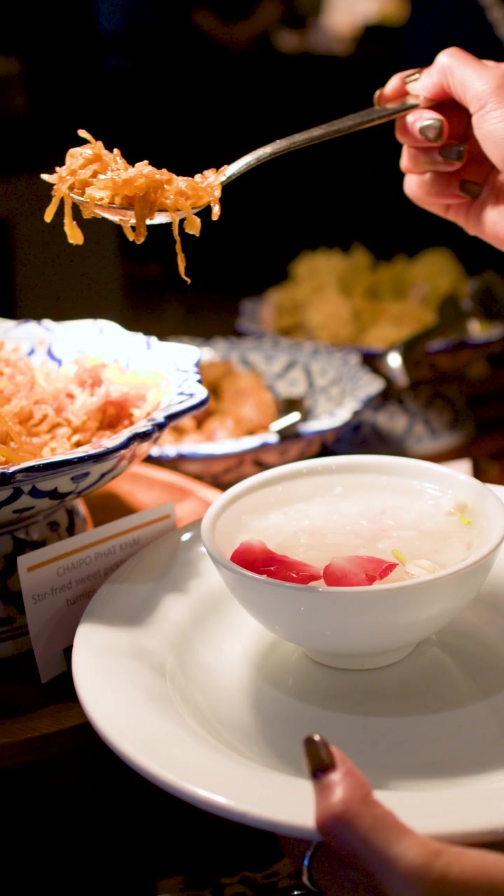 A person serves traditional Thai Khao chae chilled rice with jasmine water and rose petals