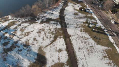 Luftbildkamera,-Die-An-Einem-Beginnenden-See,-Schnee-Und-Gras-Hochkippt