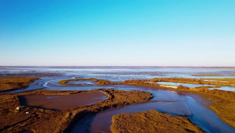 Aerial,-canal-channels-in-wet-marsh-land-on-beautiful-blue-sky-summer-day