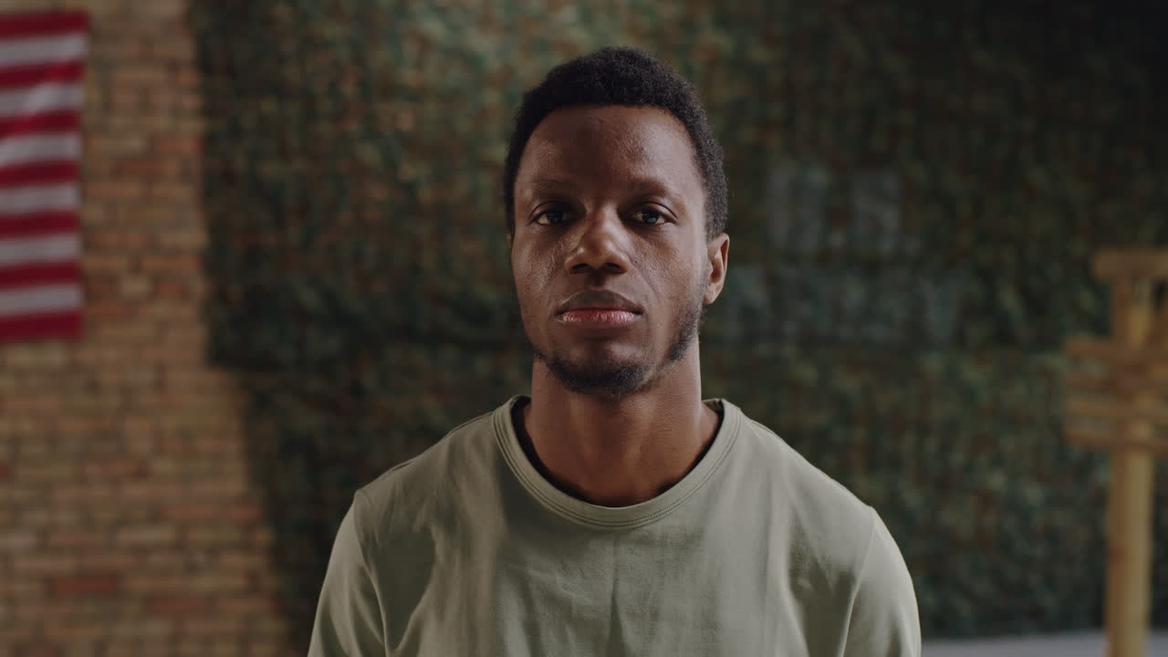 Portrait of a Man in Front of Brick Wall with Camouflage and American Flag